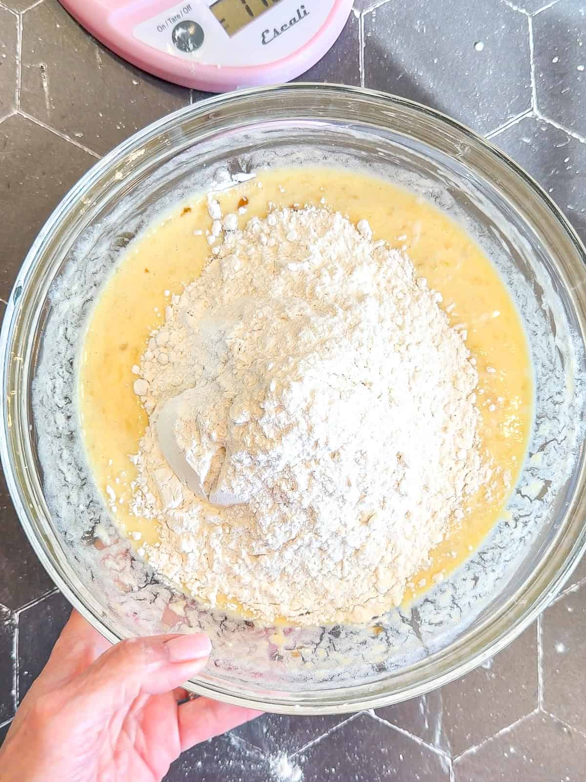 Wet ingredients and flour in a glass bowl for banana bread.
