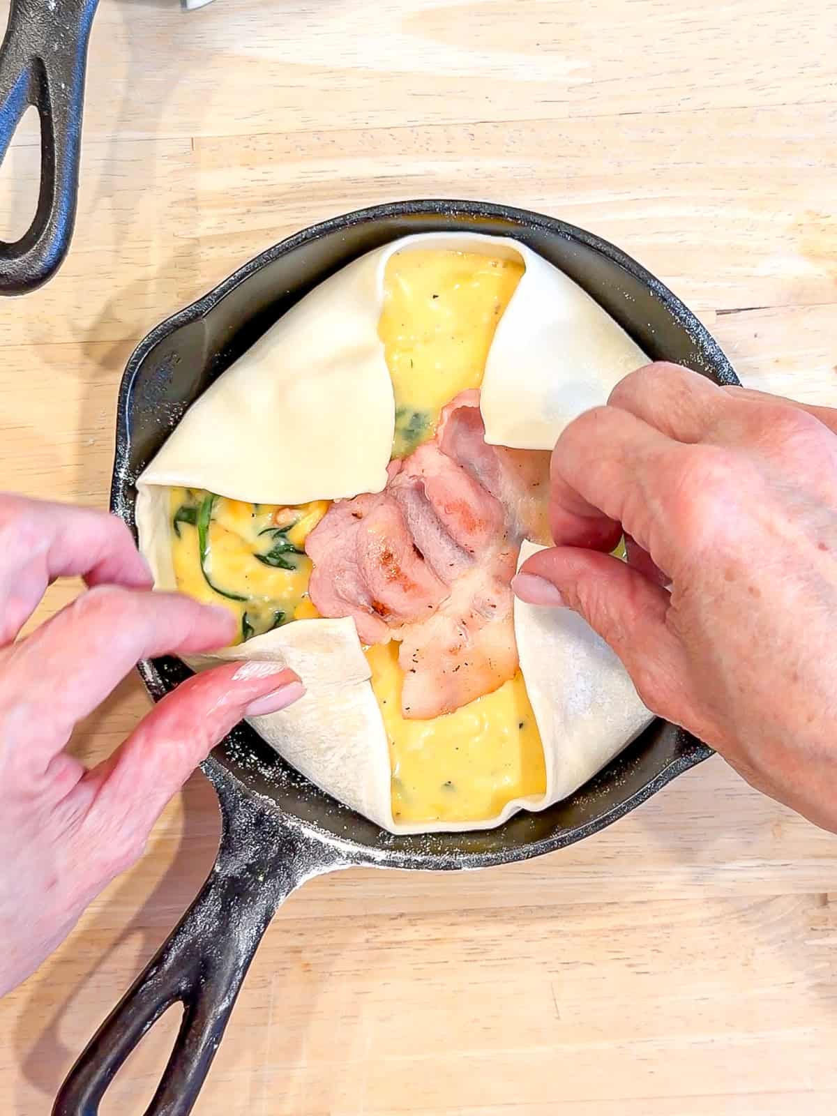 Folding puff pastry over the top of soufflé ingredients.