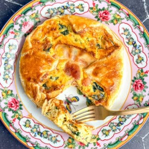 Bacon and spinach soufflé wrapped in puff pastry on a pink floral plate.