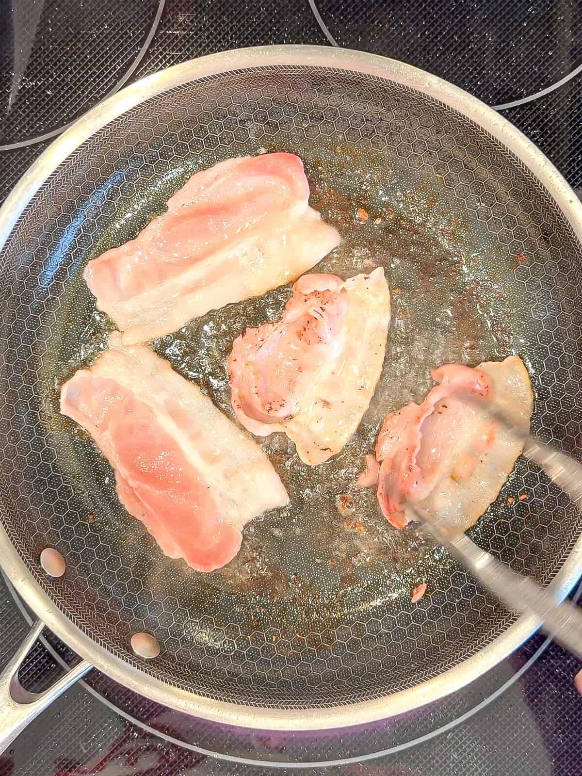Cooking bacon in a black pan.