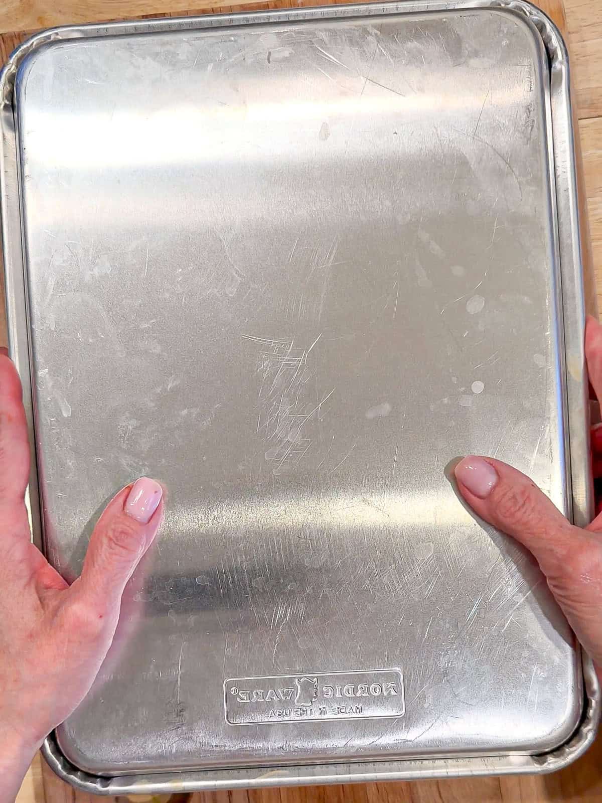 Placing a sheet pan on top of another sheet pan.