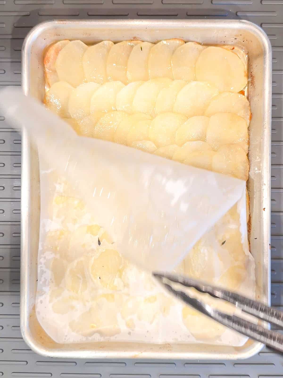 Peeling parchment paper off of potatoes in a sheet pan.