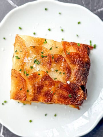 A slice of pommes anna on a white plate.