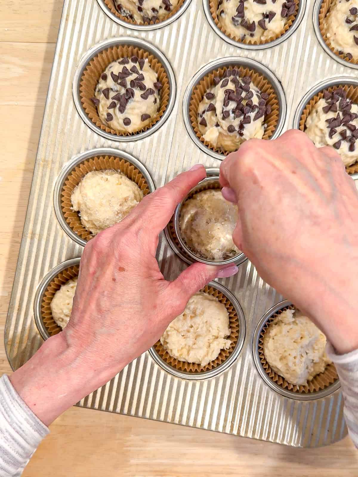Sprinkling extra chocolate chips and coarse sugar on top of soda bread muffin batter.