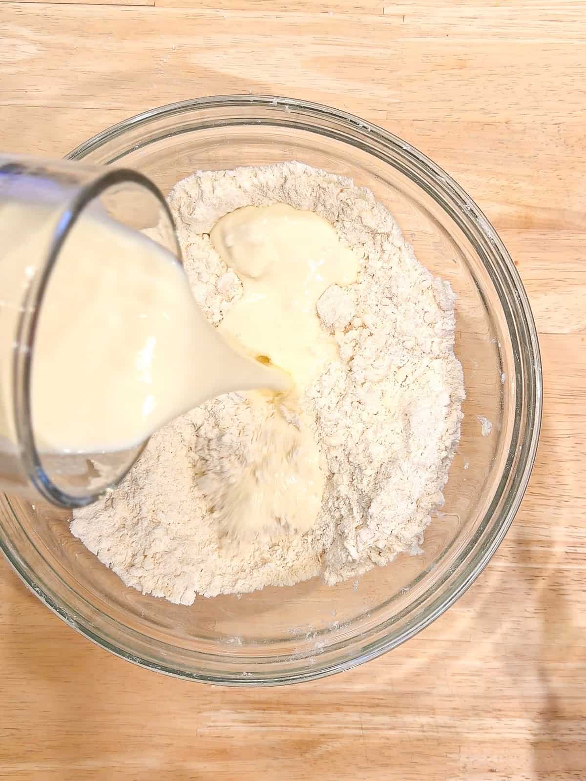 Adding wet ingredients into dry ingredients to make Irish soda bread muffins.