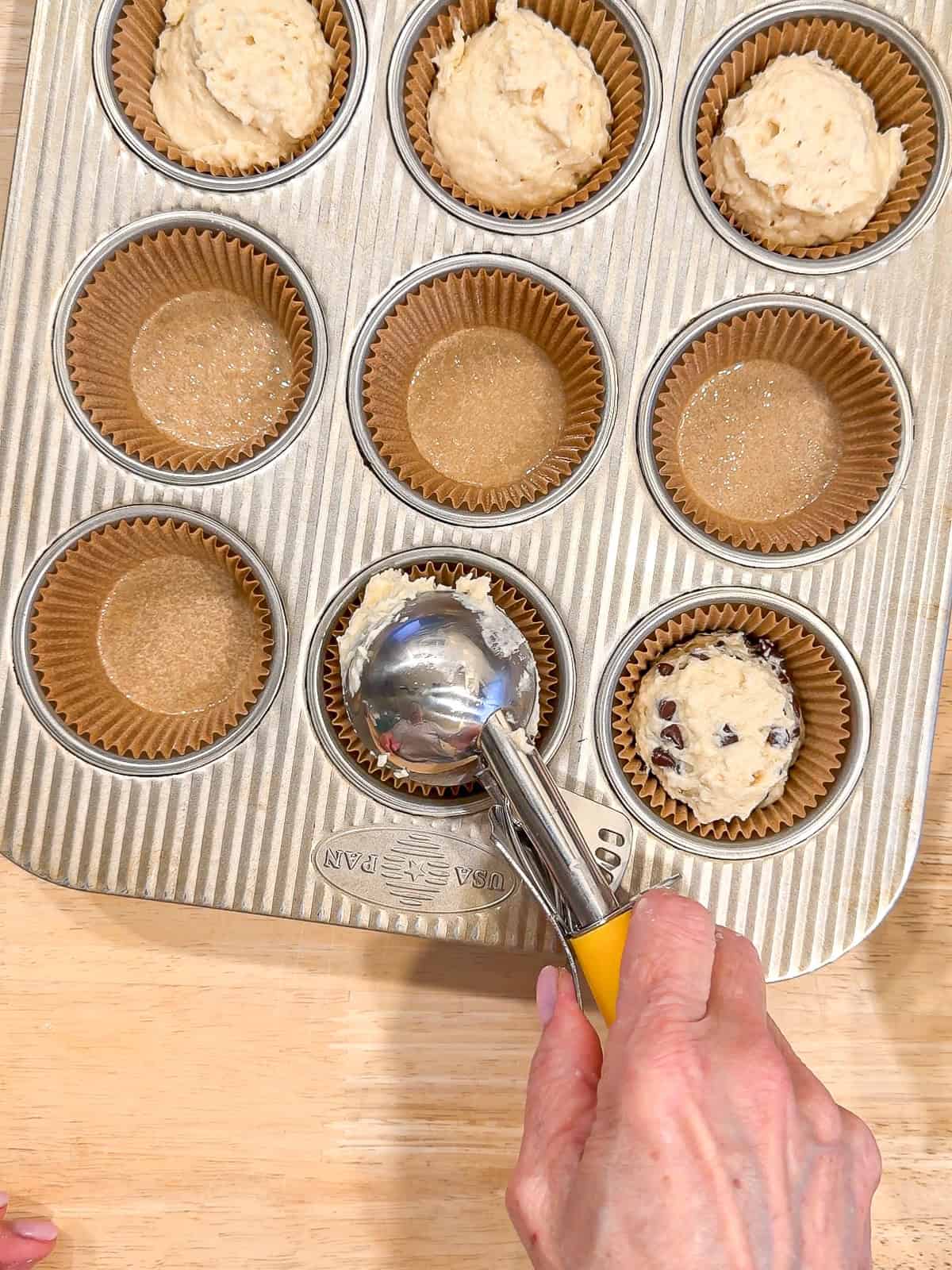 Pooping muffin batter into muffin liners.