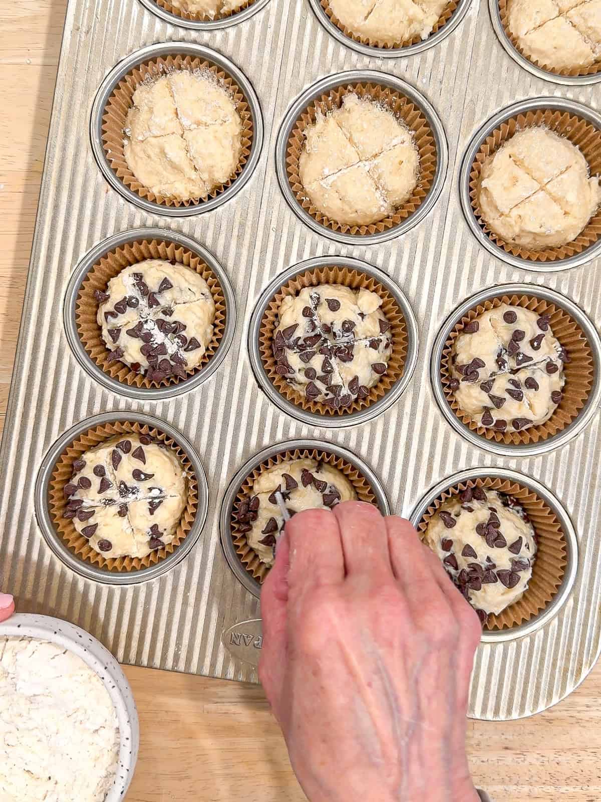 Using a safety razor to make X marks on top of muffins.