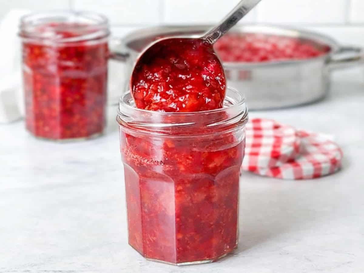 Ladling fresh strawberry jam into jars.