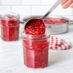 Ladling fresh strawberry jam into jars.