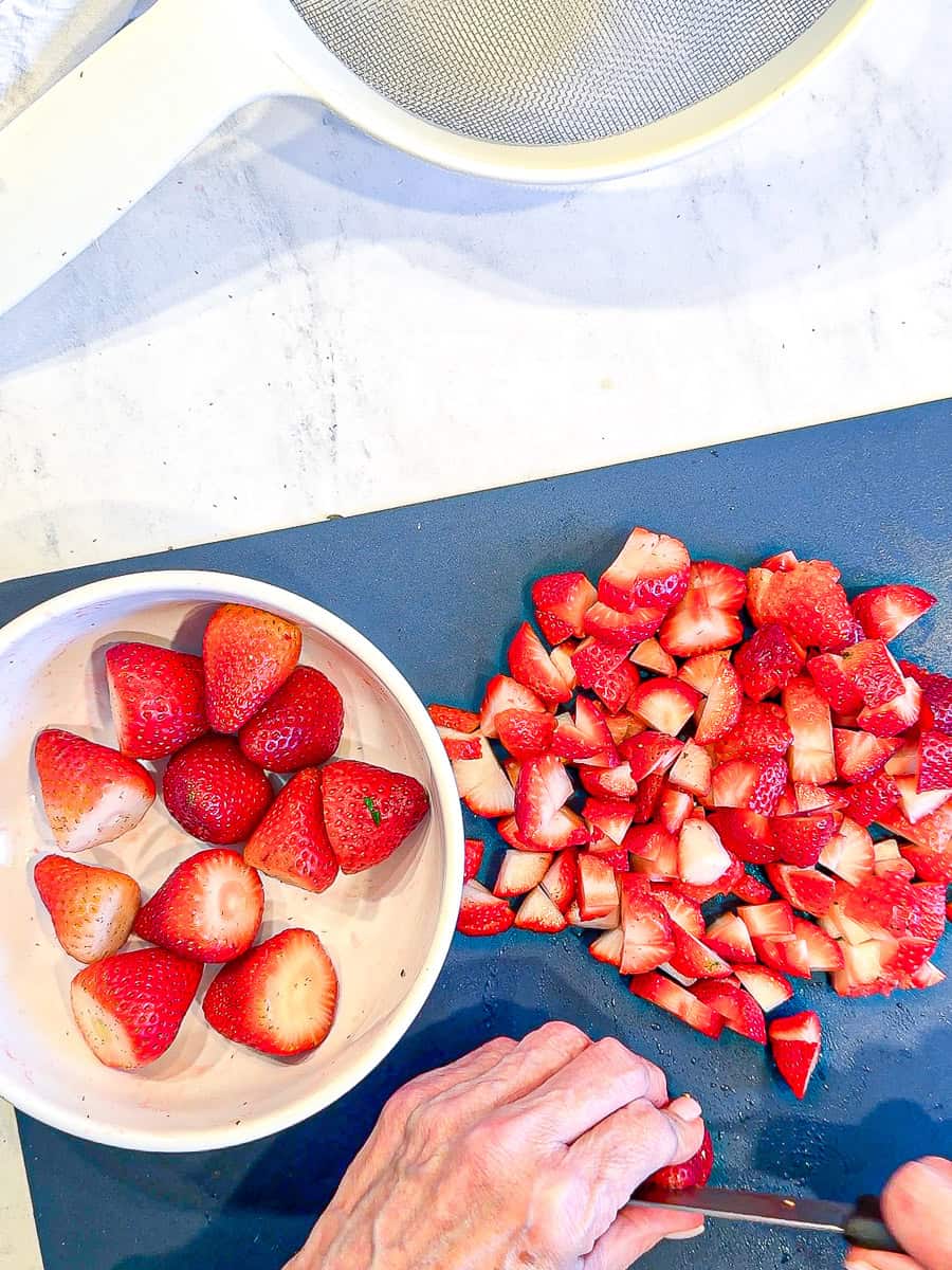 Icing strawberries on a blue cutting board.