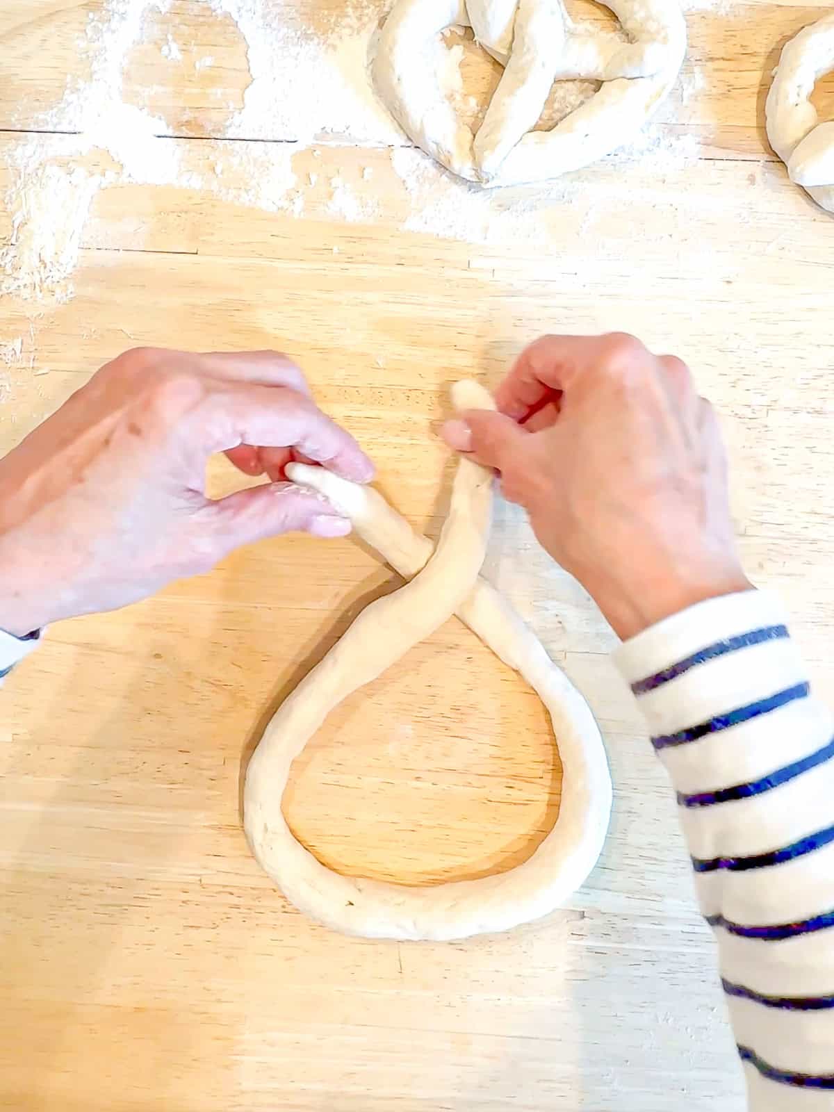 Crossing ends of pretzel dough over each other.