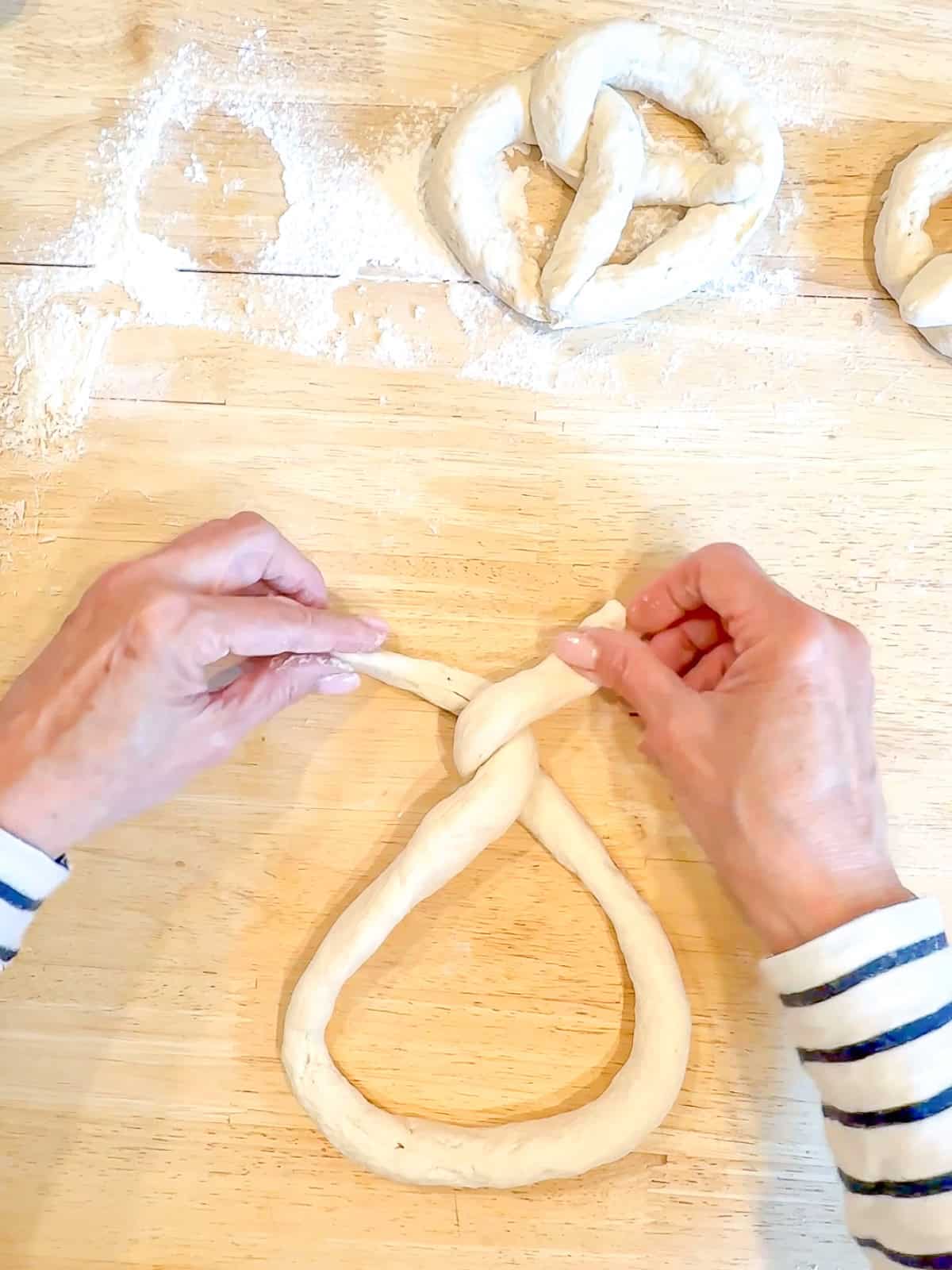 Twisting ends of pretzel dough around each other.
