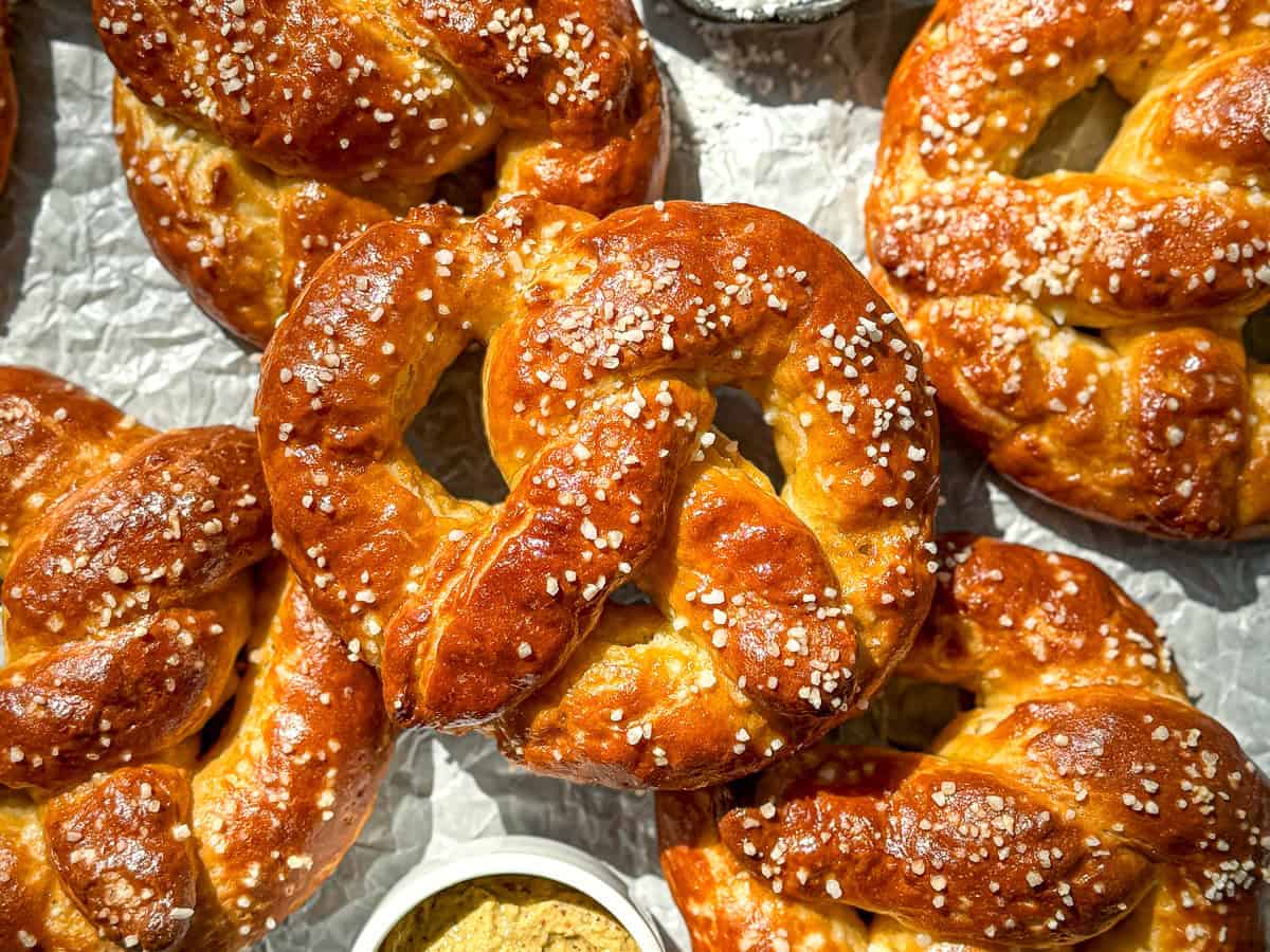 Soft pretzels on parchment paper with a dish of mustard.