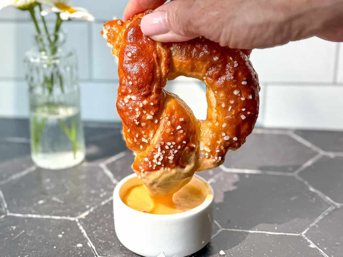 Dipping a soft pretzel into cheese sauce.