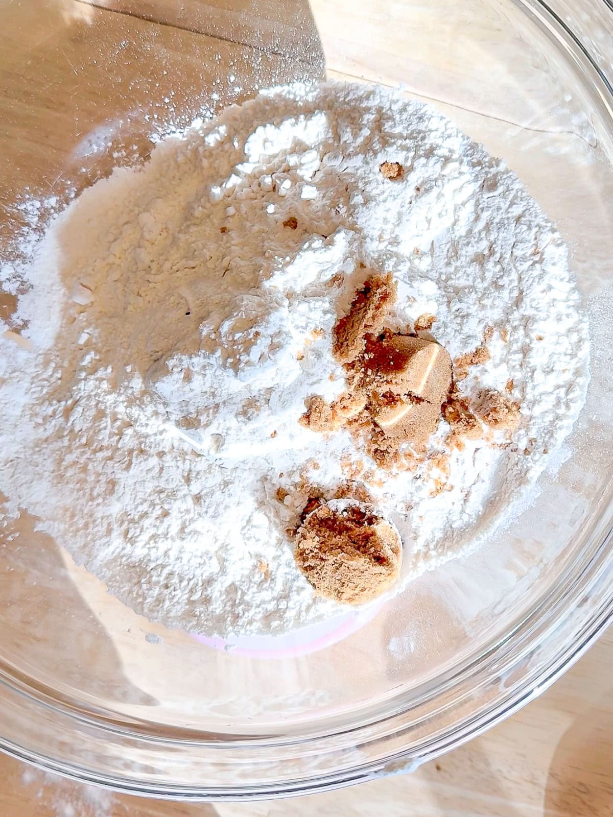 Self rising flour and brown sugar in a glass bowl.