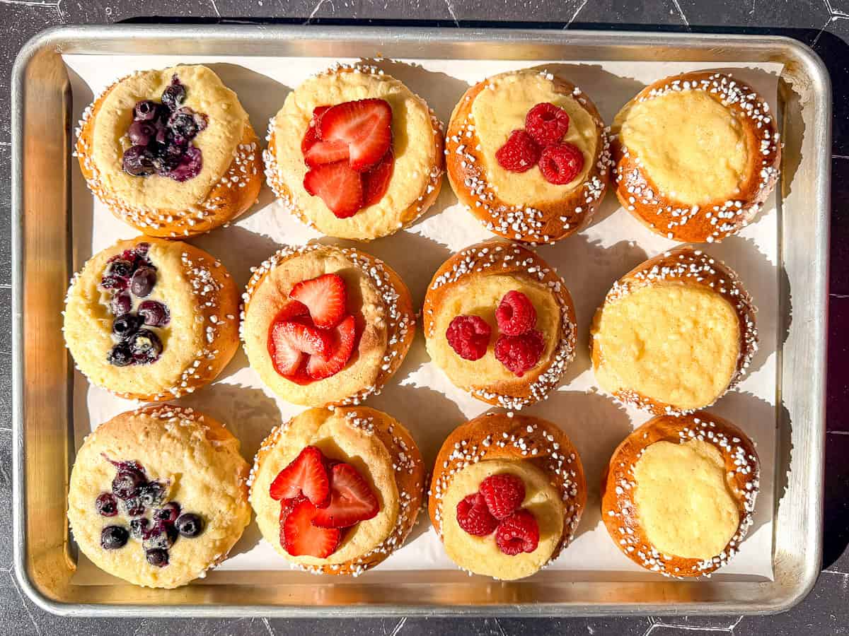 Berry topped brioche danishes on a pachment paper lined sheet pan.