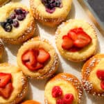 Berry topped brioche danishes on a parchment paper lined sheet pan.