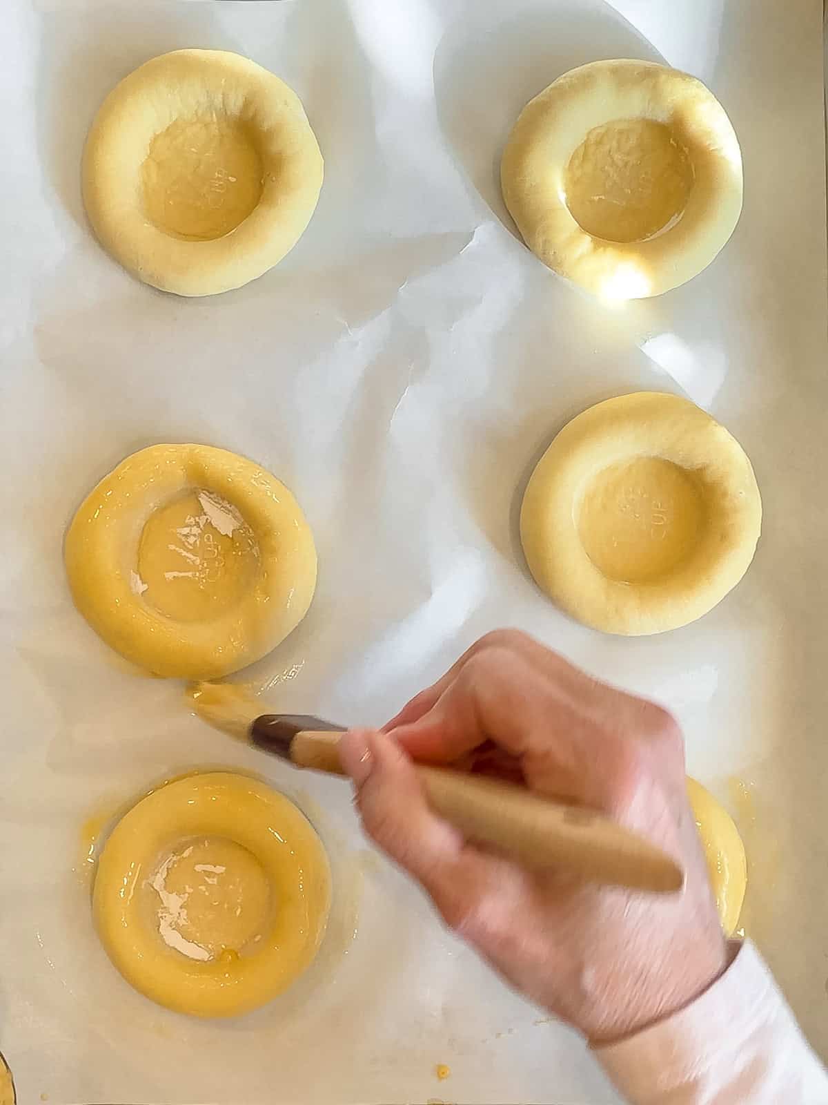 Brushing an egg wash on dough discs.