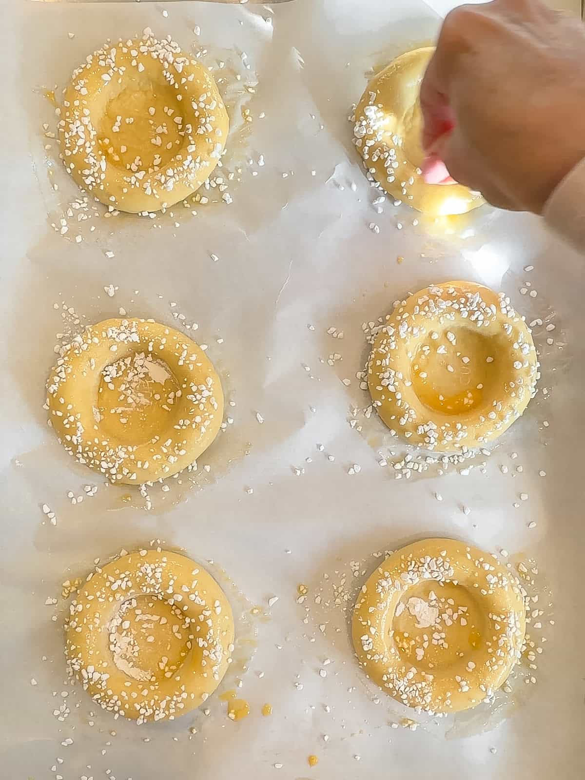 Sprinkling sugar pearls on dough discs.