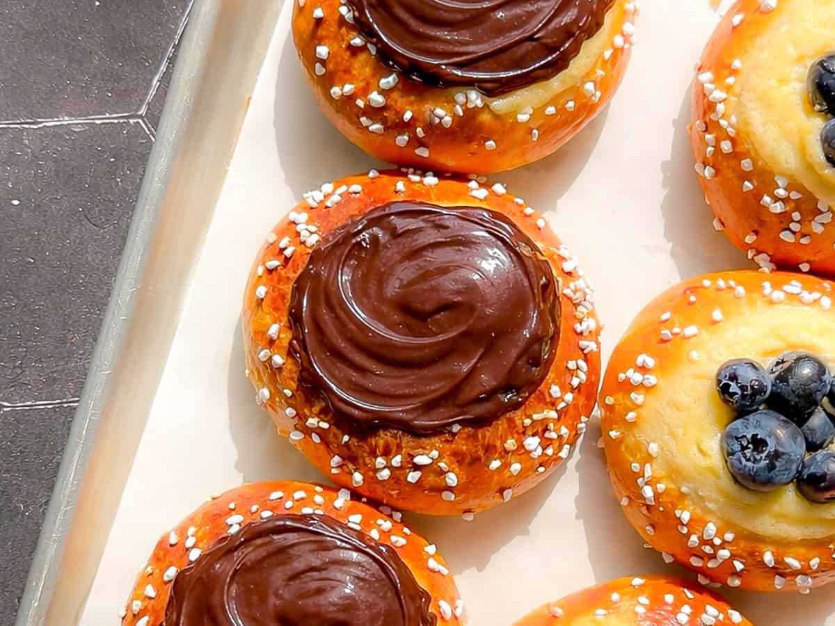 Chocolate covered brioche danish on a parchment paper lined sheet pan.