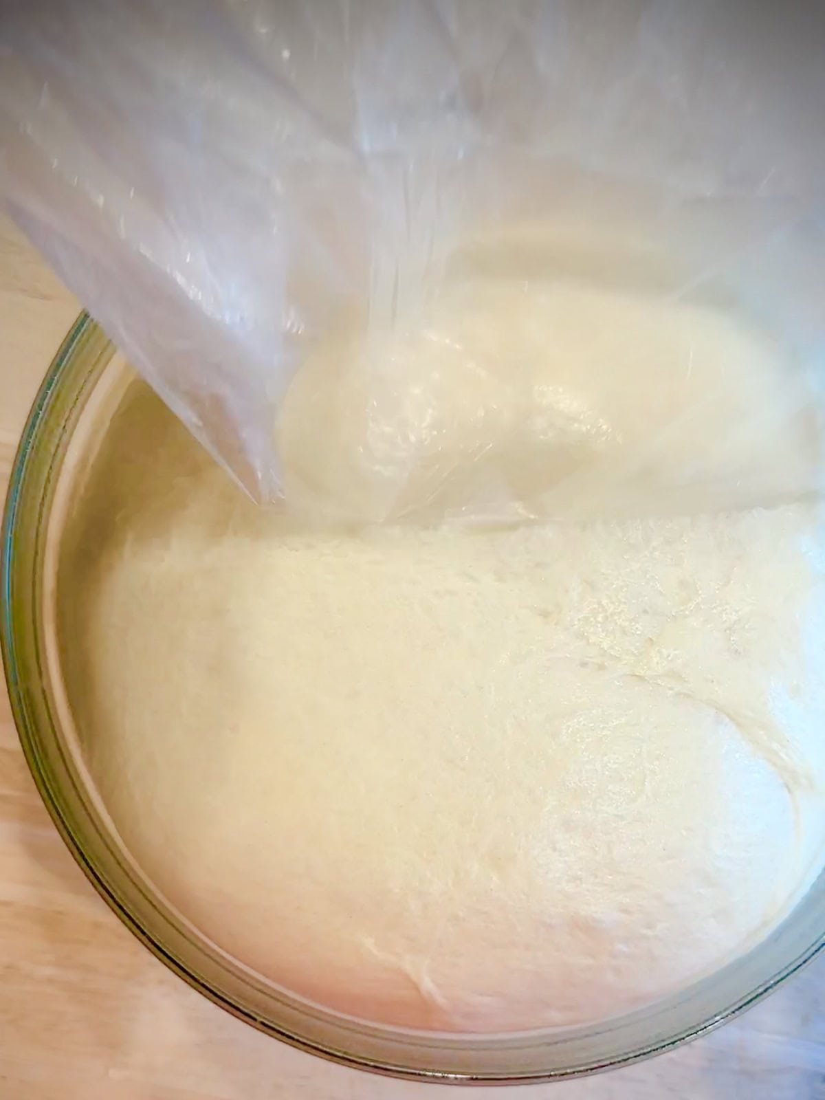 Fully risen brioche dough in a glass bowl.