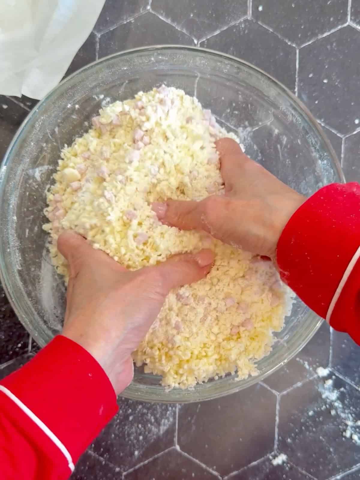 Mixing ham and cheese into dry ingredients for a glass bowl.