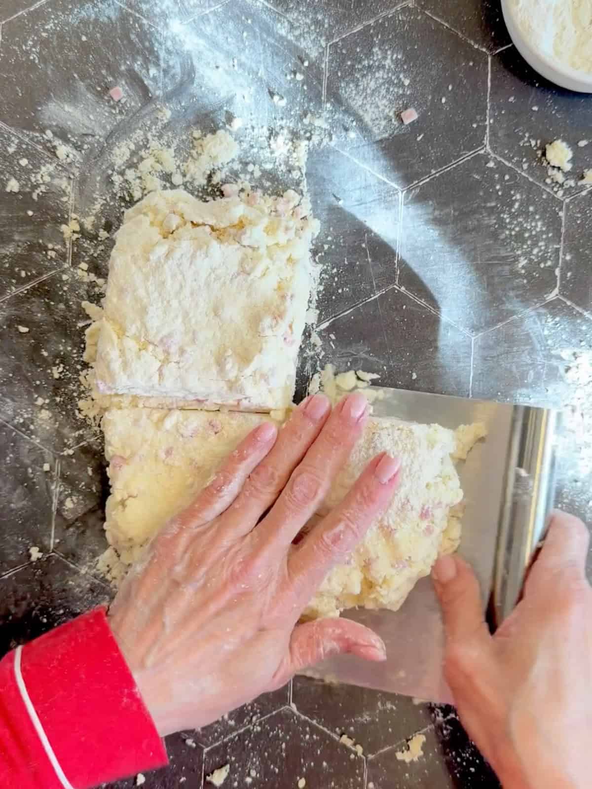 Stacking squares of biscuit dough on top of each other.