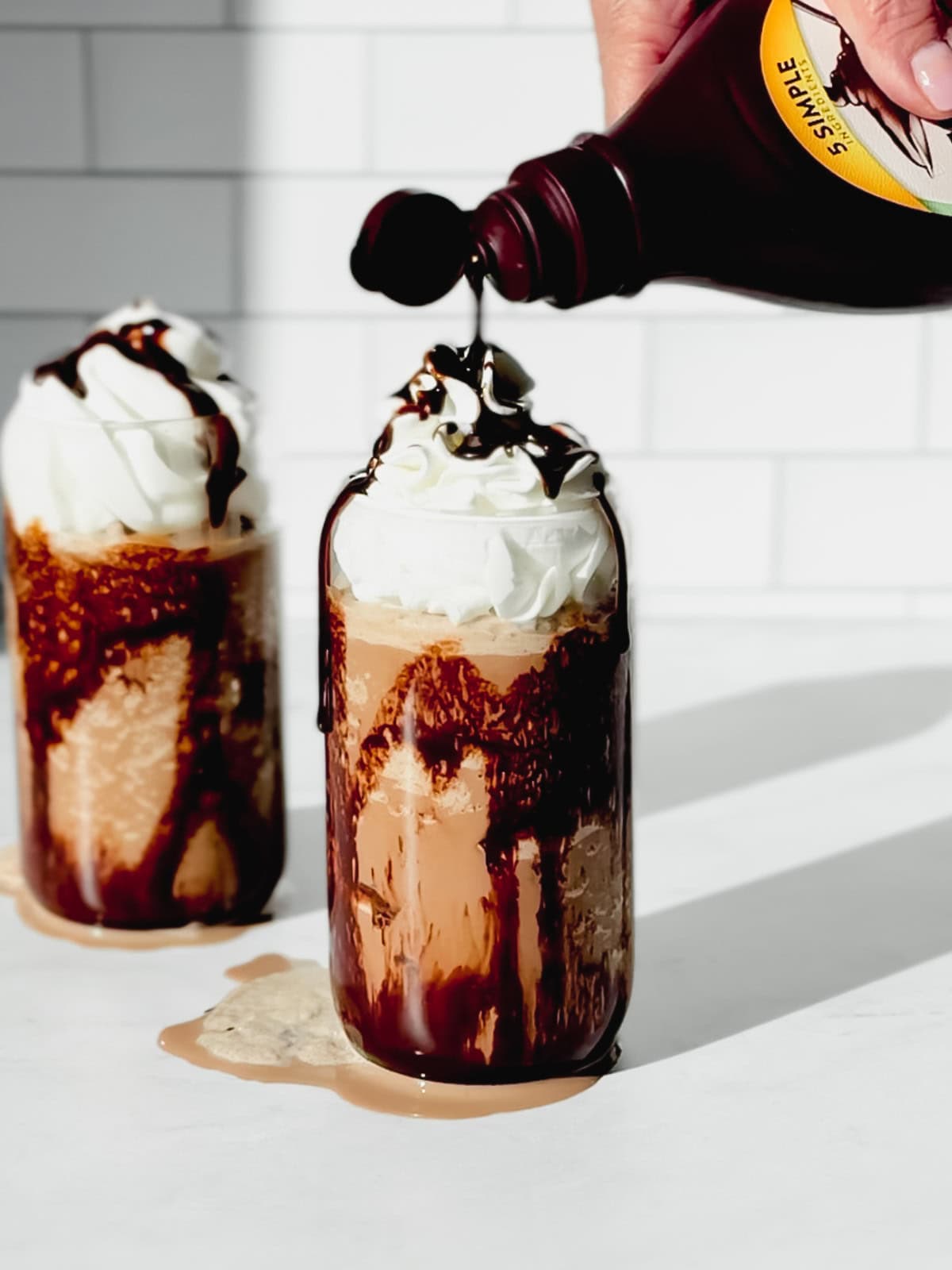 Drizzling chocolate syrup on a mocha Frappuccino.