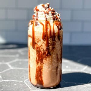 Mocha Frappuccino on a black counter with a subway tile backdrop.