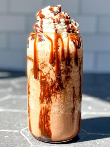 Mocha Frappuccino on a black counter with a subway tile backdrop.