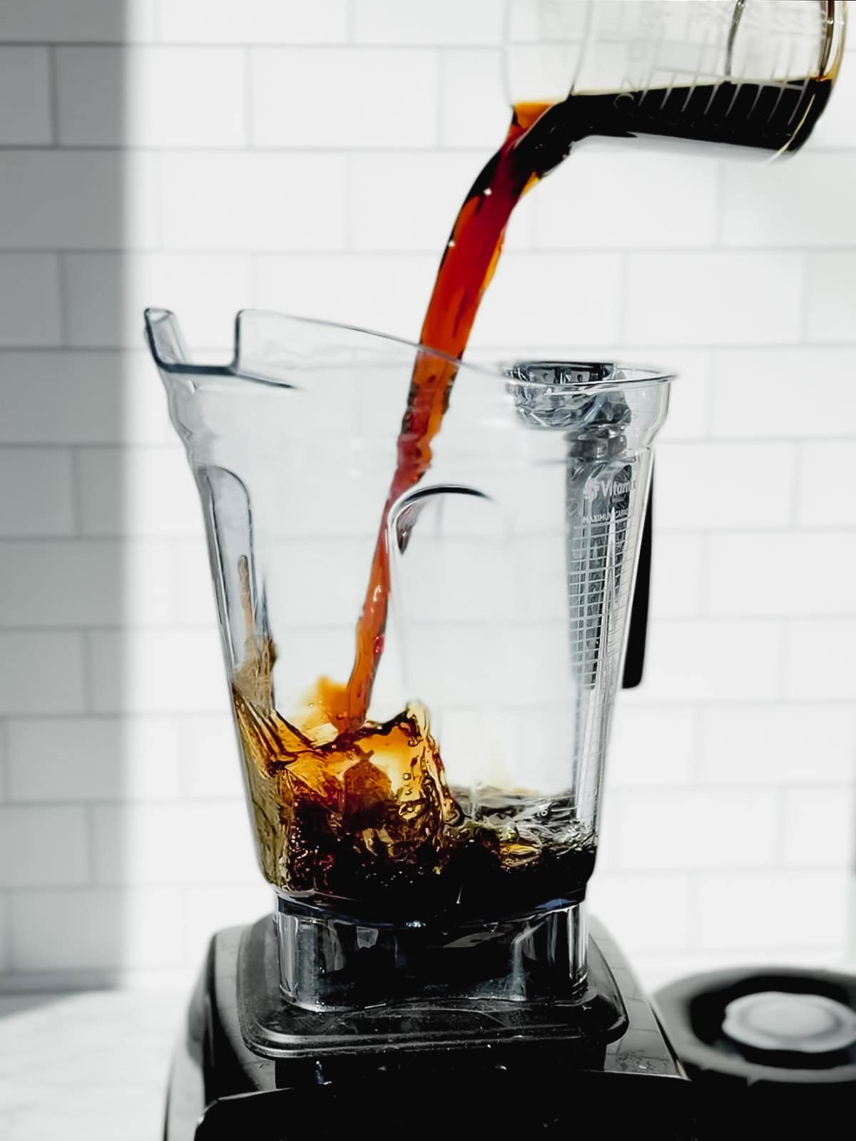 Pouring cold brew coffee into a blender.