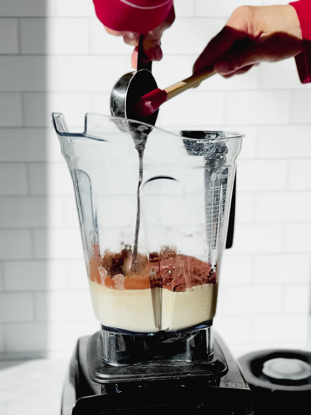 Adding chocolate syrup to a blender.