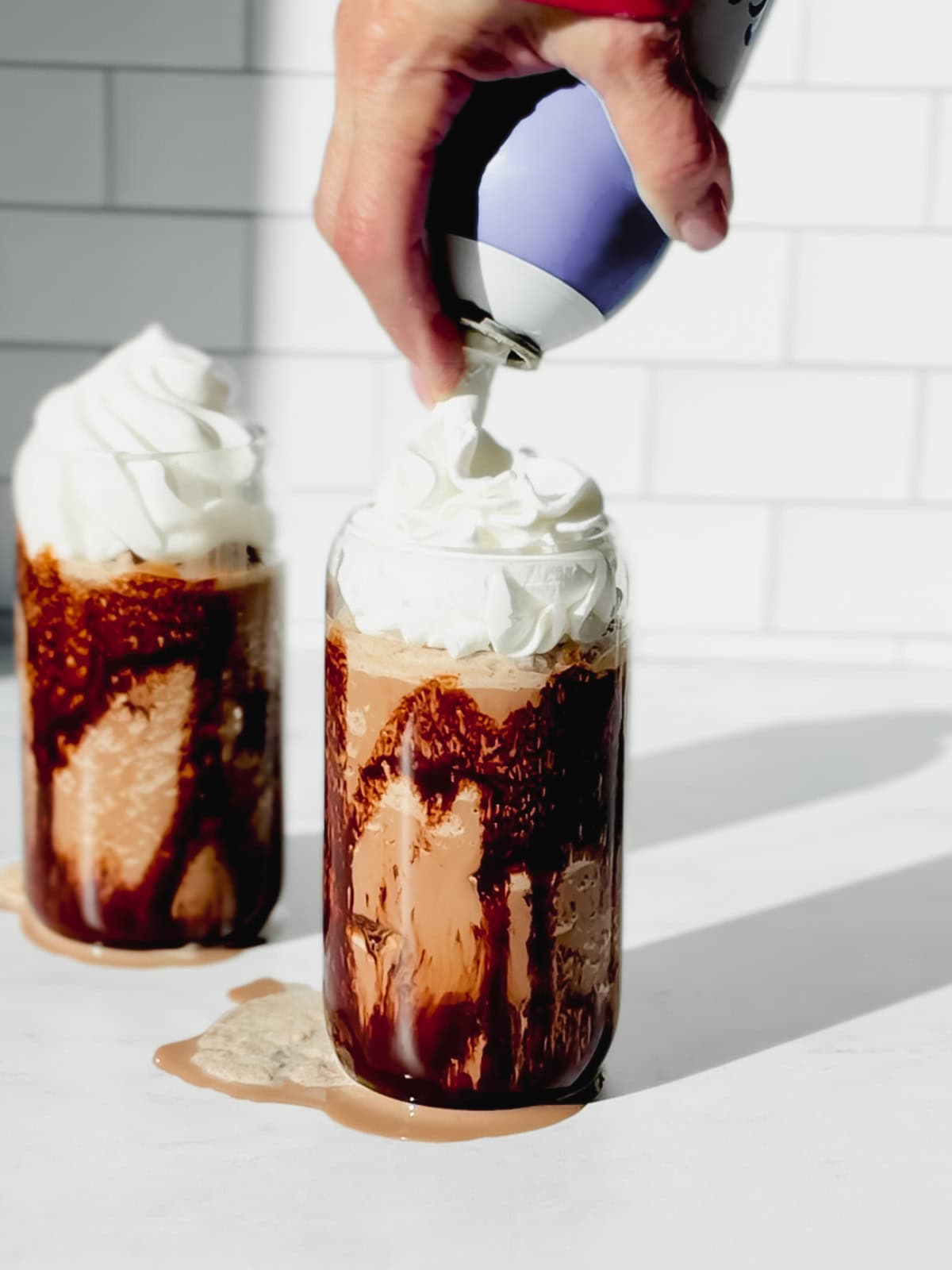 Putting whipped cream on a mocha Frappuccino.