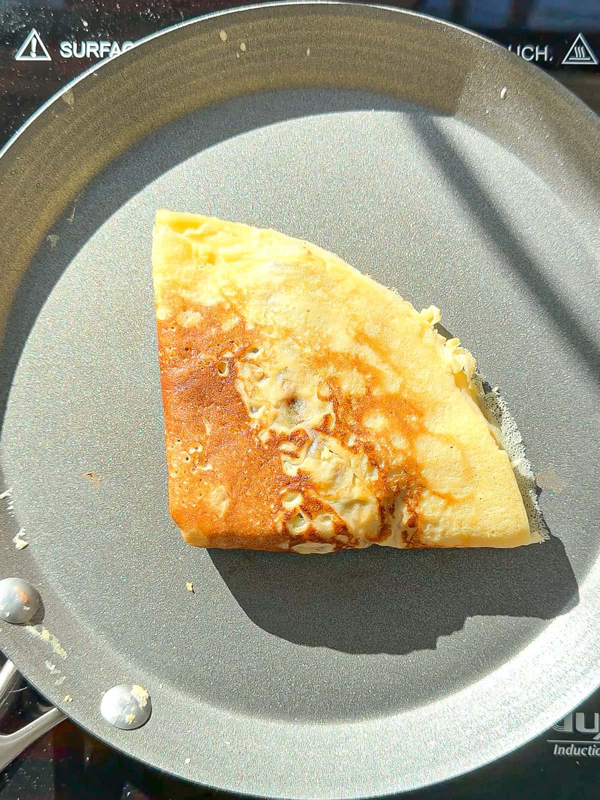 A triangular folded crêpe and a grey pan.