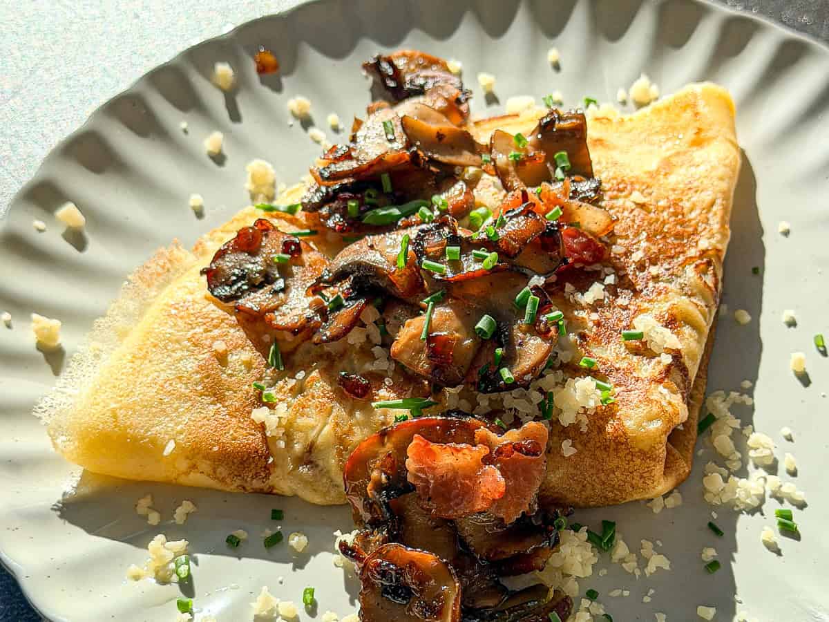 Mushroom crêpe on an ivory plate.