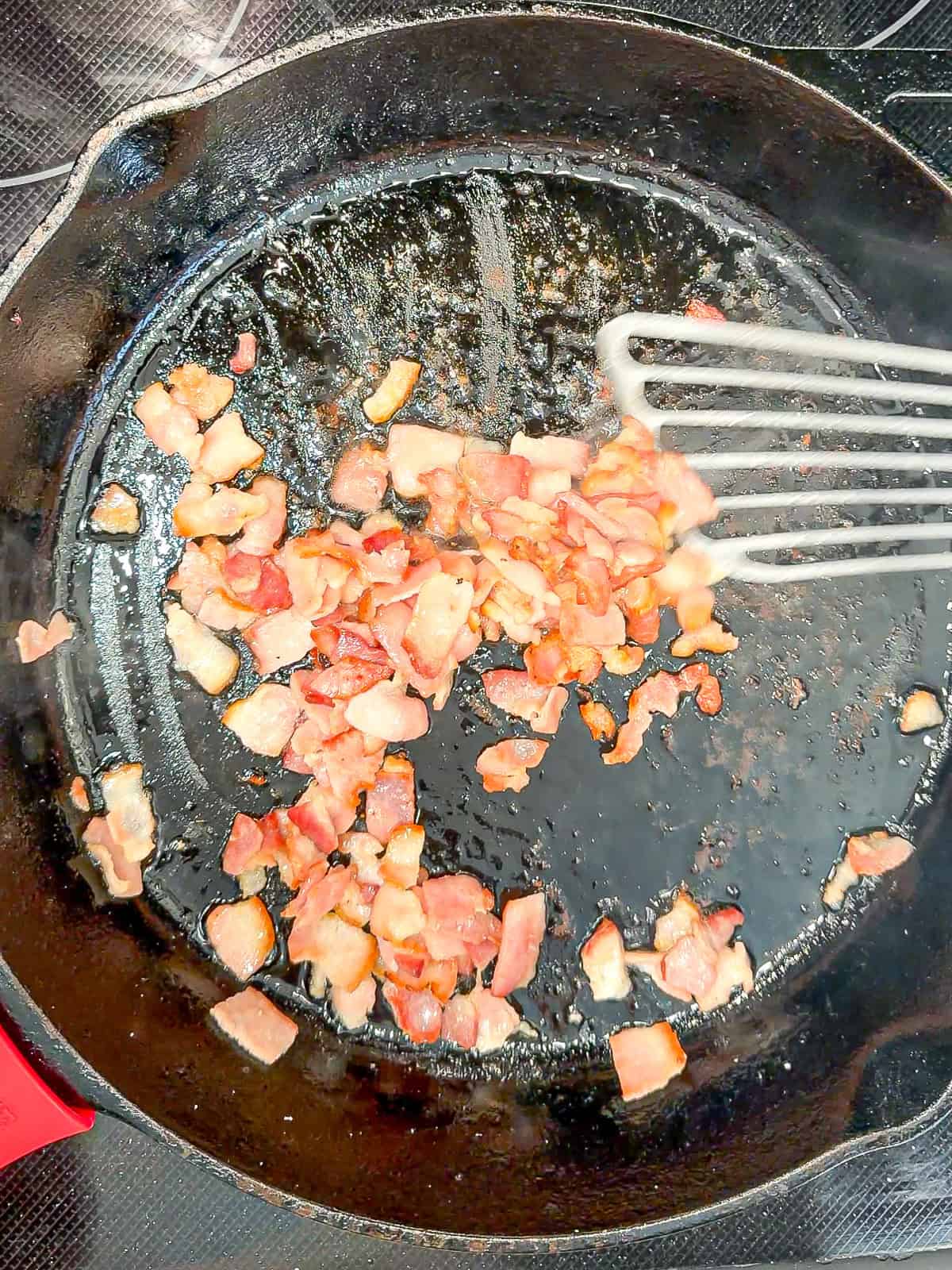 Cooking bacon in a black pan.