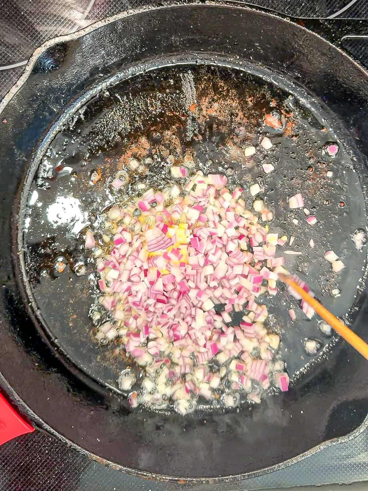 Cooking diced onions in a black pan.