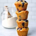 A snack of blueberry pancake muffins in front of a glass jar of pancake mix.