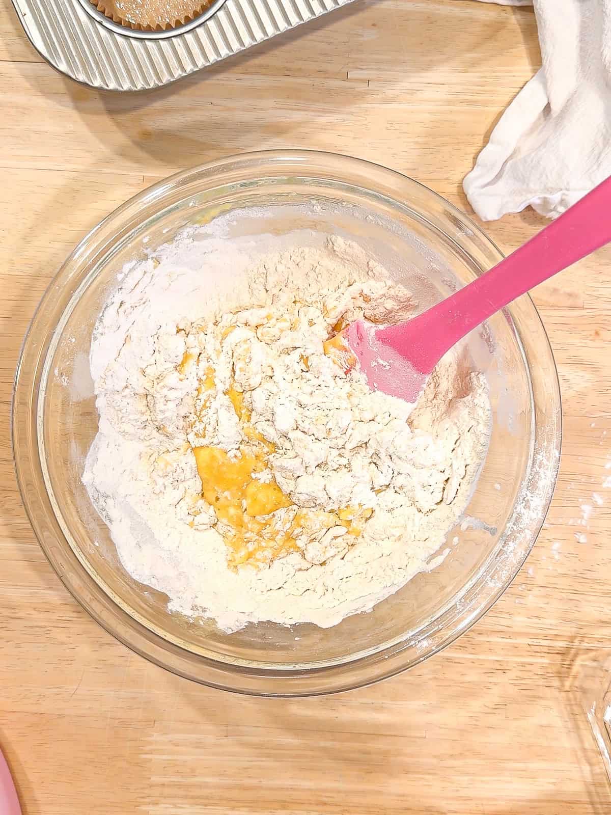 Mixing dry ingredients with wet ingredients in a glass bowl.