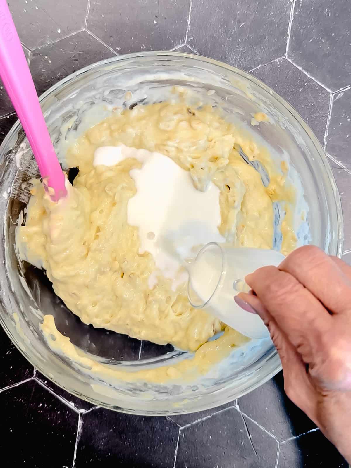 Adding milk to thin out pancake batter.