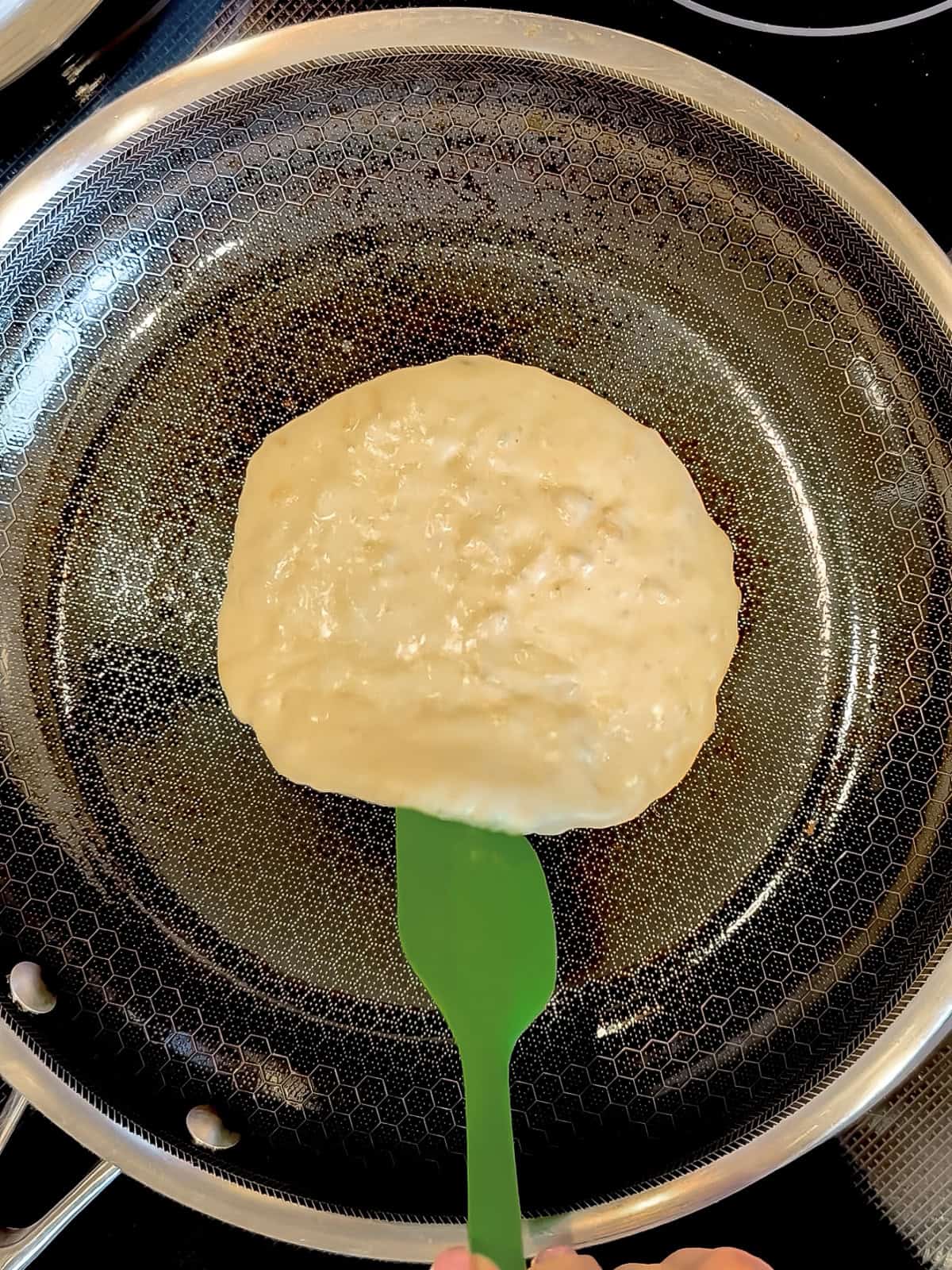 Using a thin silicone spatula to check the doneness underneath the pancake.