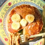 Top view of a stack of banana oatmeal pancake pancakes with bananas and a pat of butter on top.