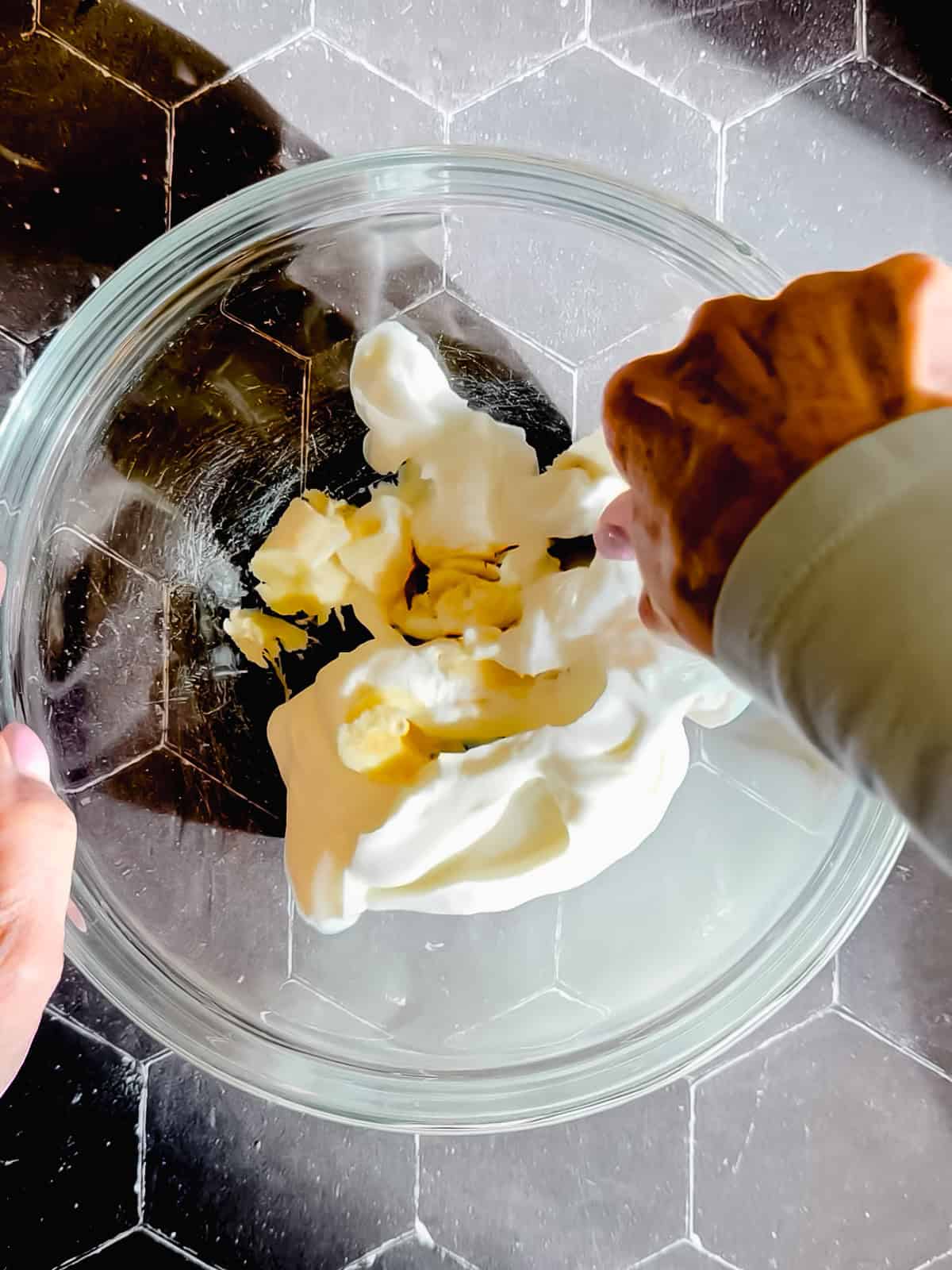 Mashing together banana with Greek yogurt in a glass bowl.