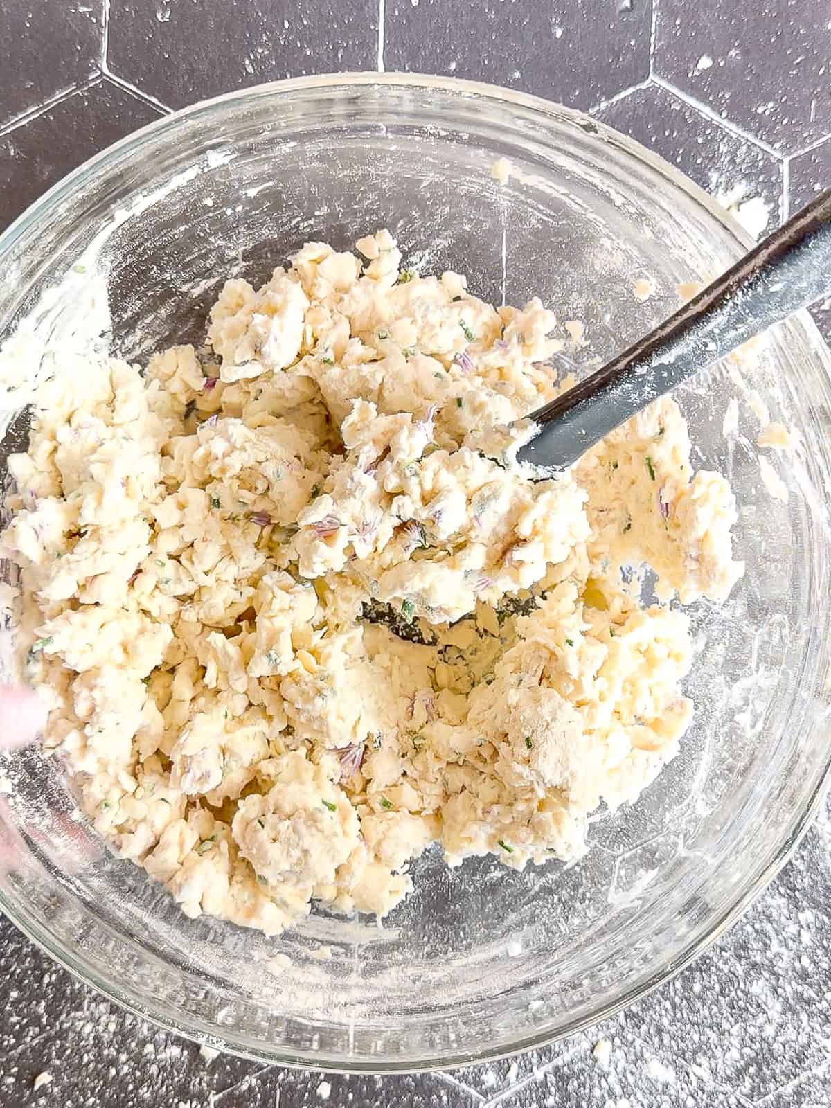 Fully mixed chive blossom biscuit dough in a glass bowl.