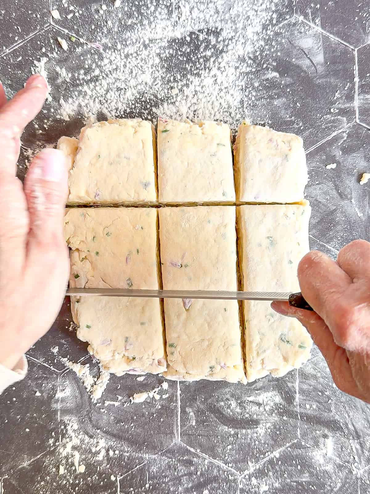 Cutting biscuit dough with a knife on a black background.