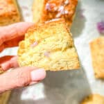 Author's hand holding a chive blossom biscuit.