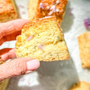 Author's hand holding a chive blossom biscuit.