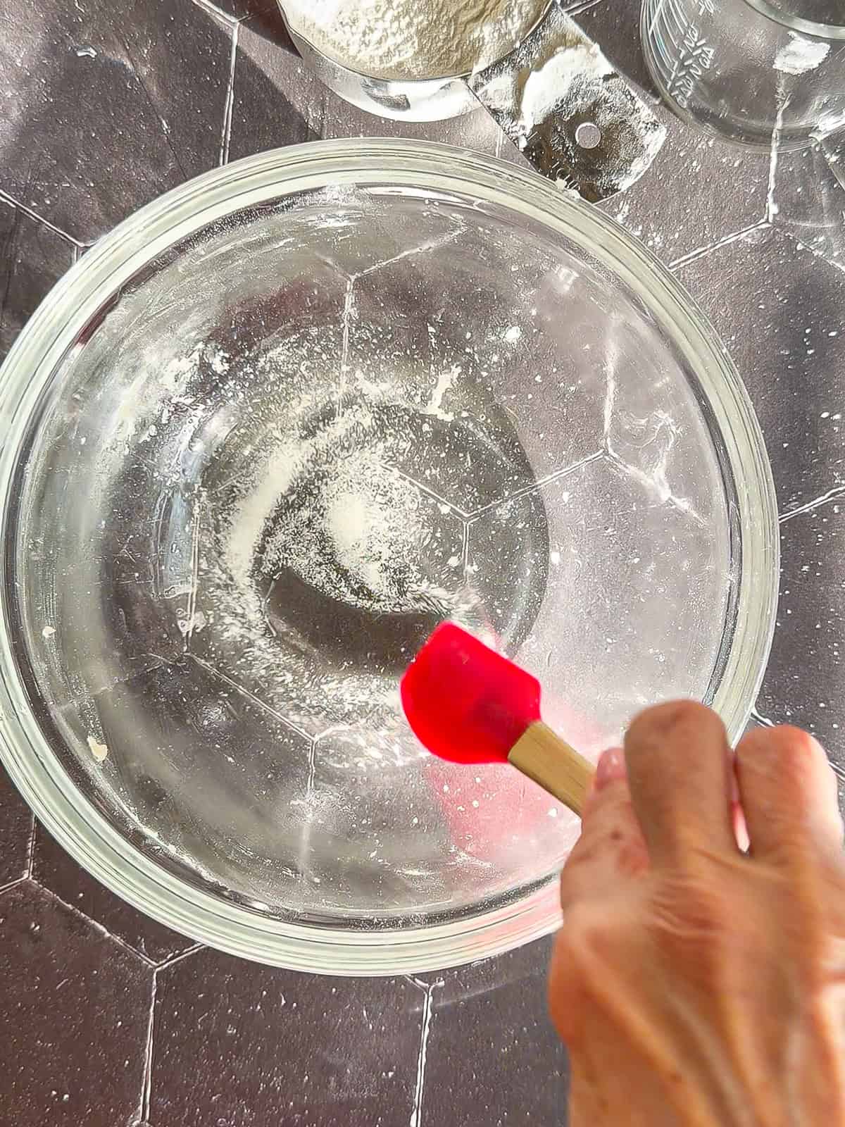Stirring salt into melted lard in a glass bowl.