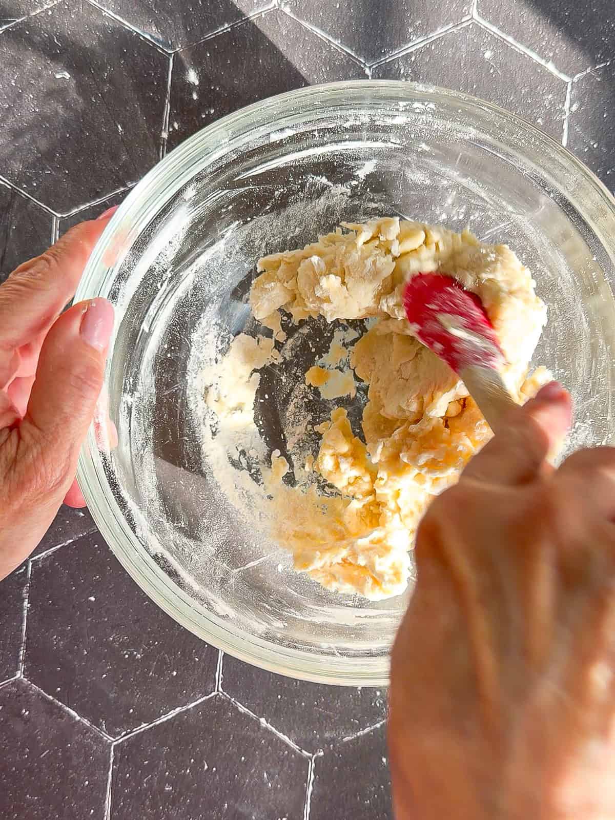 Mixing tortilla dough in a glass bowl.