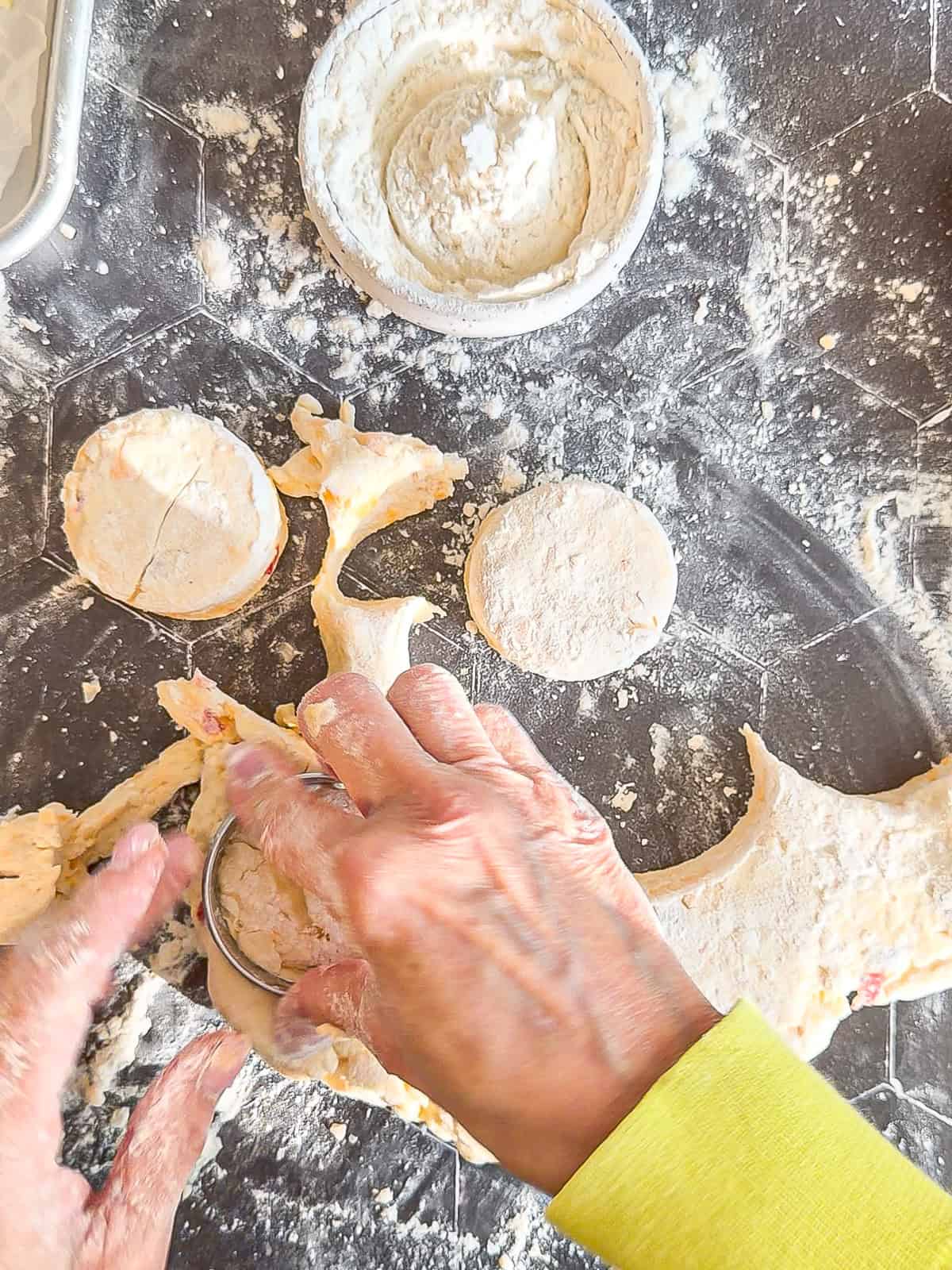 Cutting out pimento cheese biscuits on a black background.